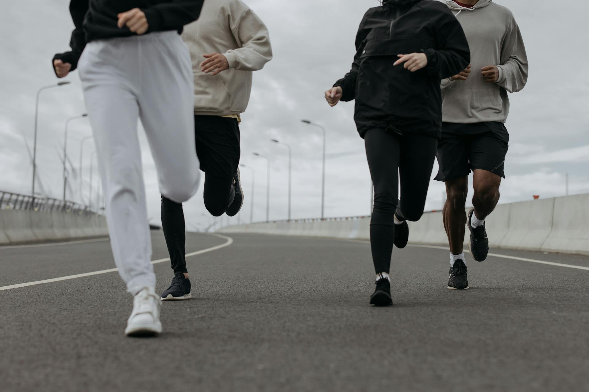 A group of people jogging on an open road, dressed in stylish and comfortable activewear. The image captures movement, energy, and a dynamic lifestyle, reflecting a sporty and fitness-oriented fashion aesthetic.