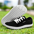 Black sneakers with white soles on grass